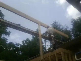Carpenter setting a ridge beam over a new addition frame — Ice Dam Removal by Roofing Brothers in Larimore