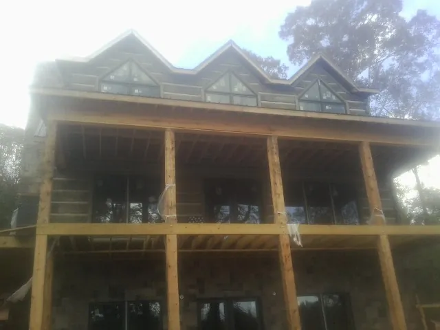 Dormers and porch framing on a large log home under construction — Roof Coating work by our crew in Larimore