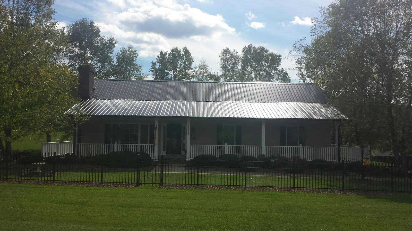 Gray metal roof on a brick ranch with a full width front porch — Gutter Guard Installation work by our crew in Larimore