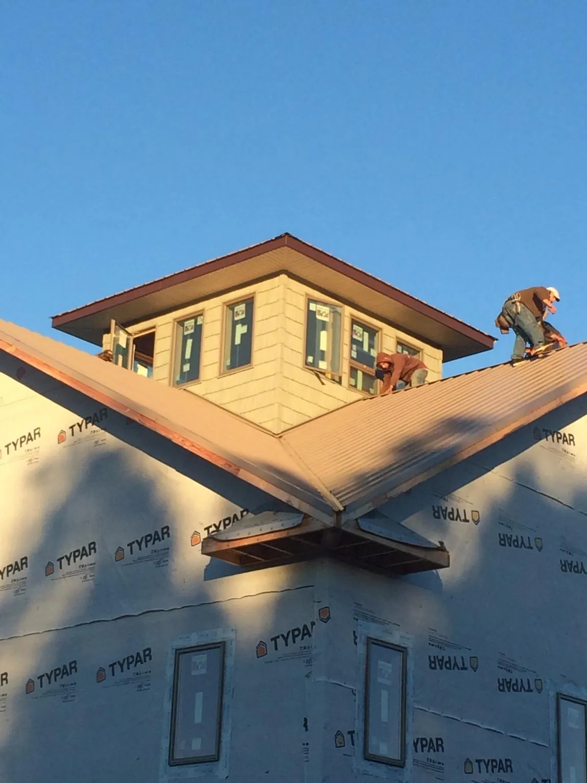 Roofers working around a rooftop cupola on a new metal roof at sunset — Roof Waterproofing in Larimore by Roofing Brothers